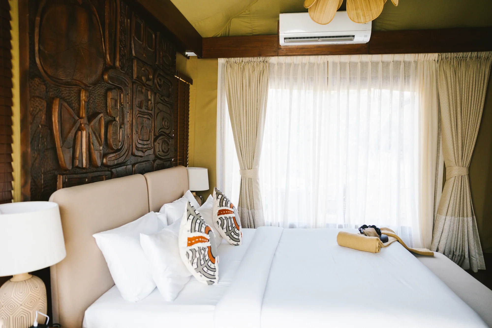 An inviting bed with natural fabrics and handcrafted wood details at Founders Camp